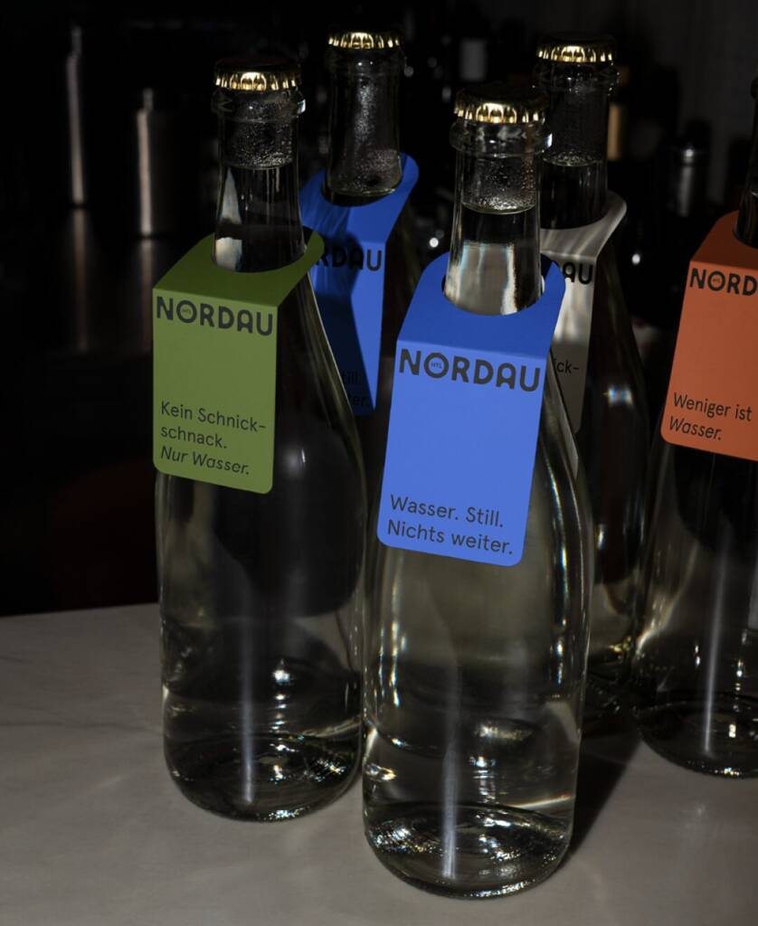 Nordau Wasserflaschen mit blauem Etikett auf dunklem Hintergrund