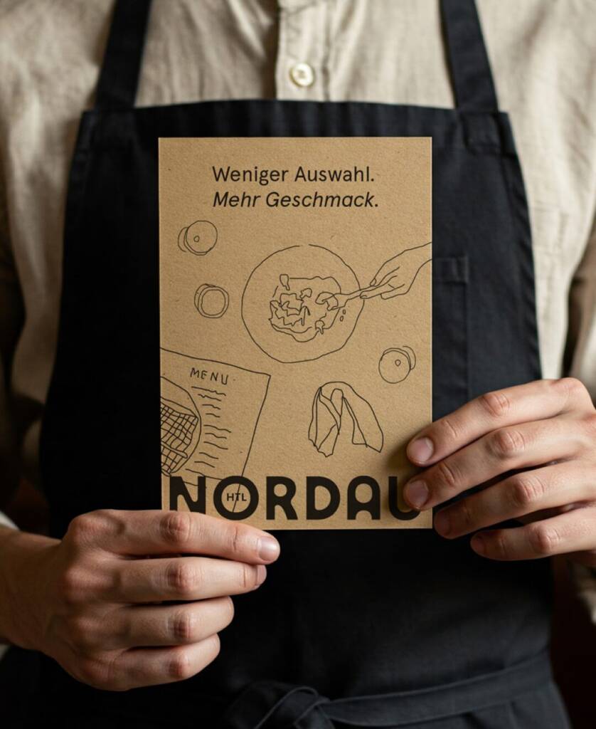 Serviceperson hält Nordau Speisekarte mit Schriftzug »Weniger Auswahl, mehr Geschmack«